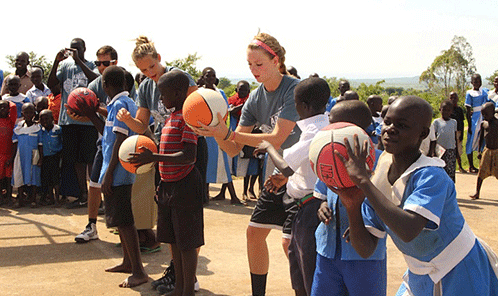 NNU's Katie Swanson shows her shooting style to Uganda children.